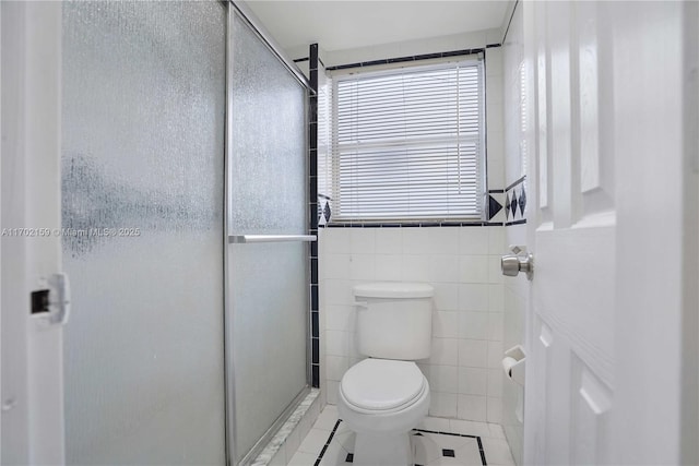 bathroom with tile patterned floors, an enclosed shower, tile walls, and toilet