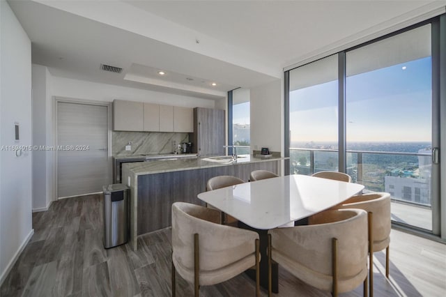 dining space with a wall of windows, dark wood-type flooring, and sink