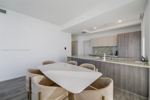 dining room featuring dark hardwood / wood-style flooring, a tray ceiling, and sink