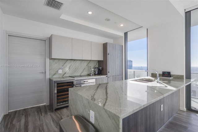 kitchen with light stone countertops, stainless steel oven, wine cooler, dark hardwood / wood-style flooring, and kitchen peninsula