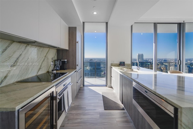 kitchen with decorative backsplash, black electric cooktop, wood-type flooring, white cabinetry, and wine cooler