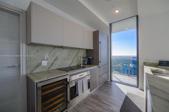 kitchen with tasteful backsplash, wine cooler, light stone counters, light hardwood / wood-style flooring, and black electric cooktop