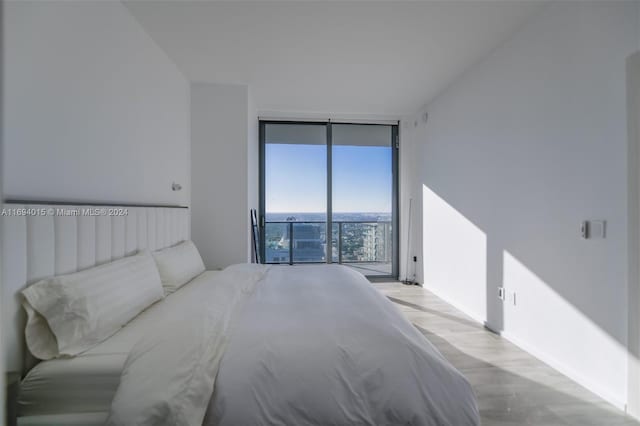 bedroom with access to outside, expansive windows, and light wood-type flooring