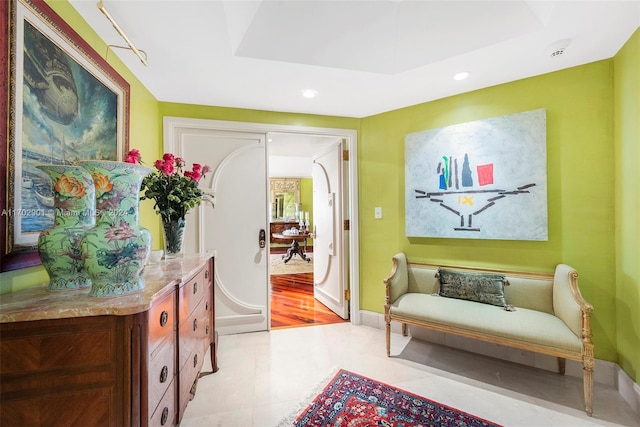 sitting room featuring light wood-type flooring and a raised ceiling