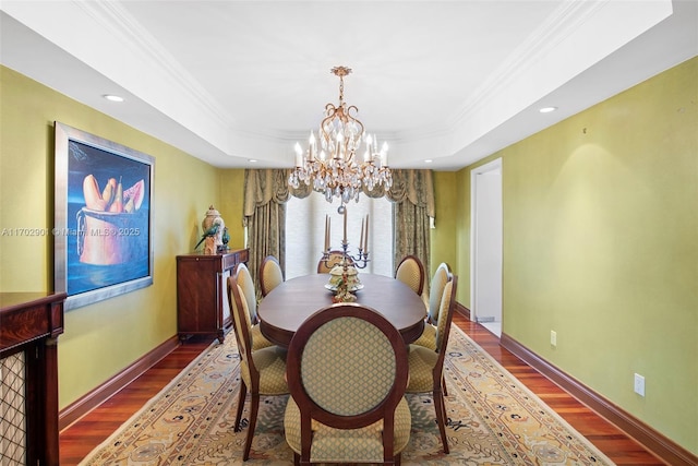 dining room with ornamental molding, a tray ceiling, a chandelier, and wood finished floors