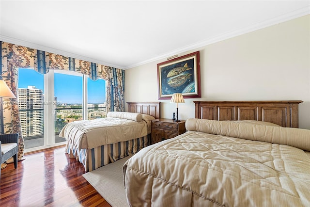 bedroom featuring a city view, access to outside, crown molding, and dark wood finished floors