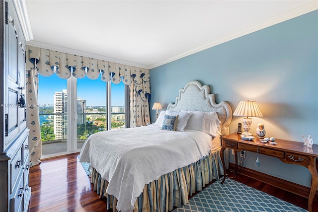 bedroom featuring ornamental molding, baseboards, wood finished floors, and a city view