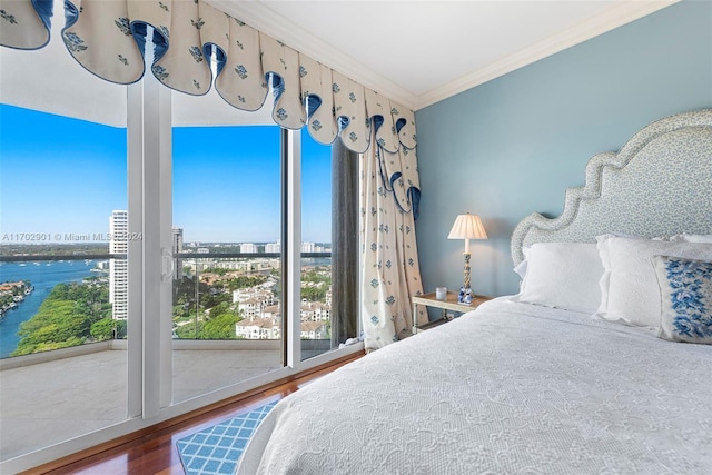 bedroom with a water view, wood-type flooring, and ornamental molding