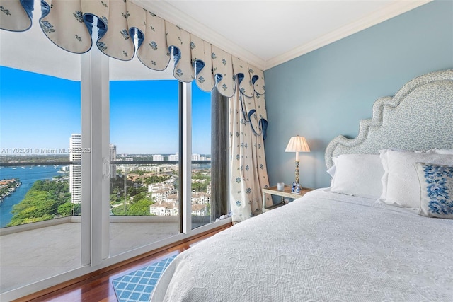 bedroom with ornamental molding and wood finished floors