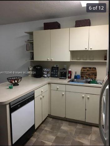 kitchen featuring white dishwasher, white cabinets, and sink