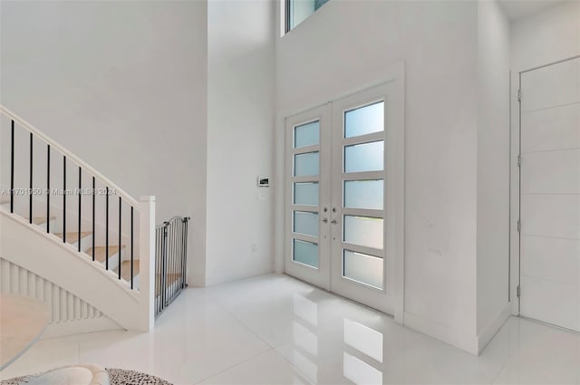 entryway with tile patterned flooring, french doors, and a high ceiling