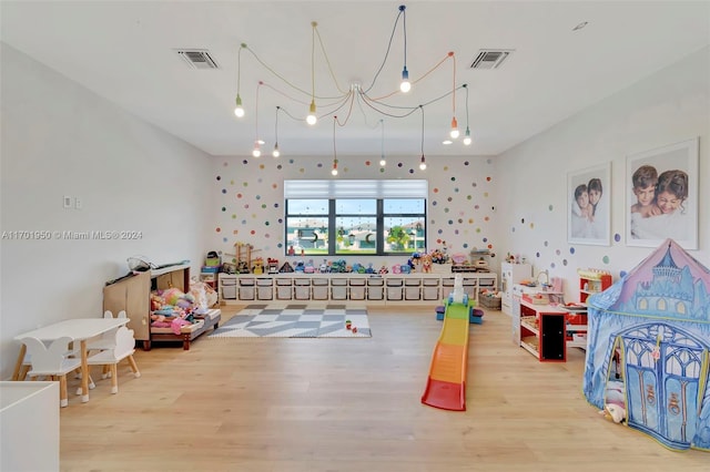 rec room with hardwood / wood-style floors and a chandelier