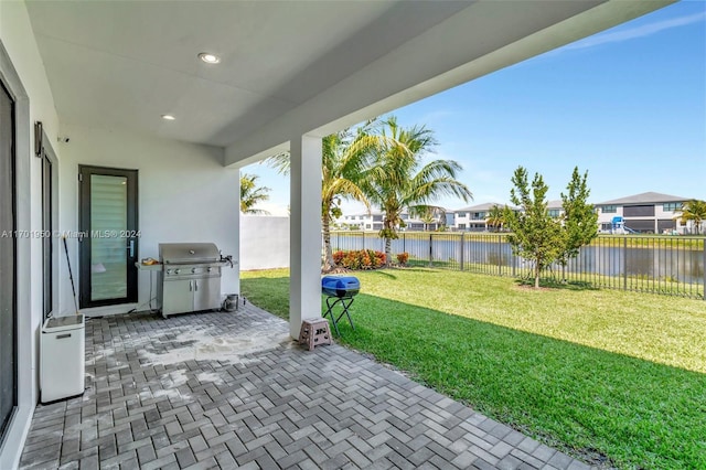 view of patio with grilling area and a water view