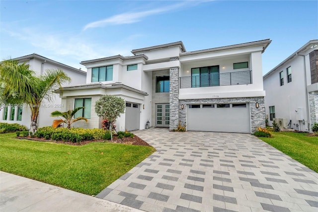 view of front of property featuring a balcony, a front lawn, and a garage