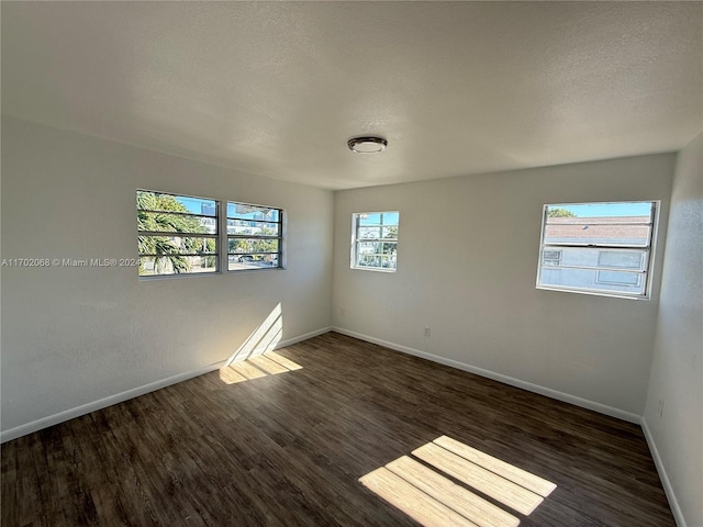 unfurnished room featuring a textured ceiling and dark hardwood / wood-style flooring