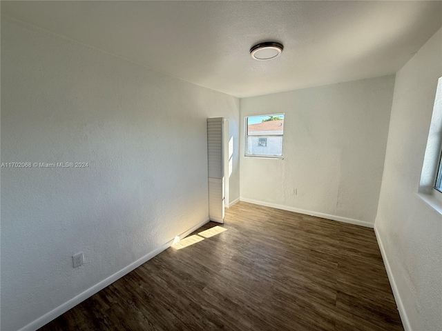 unfurnished room with dark hardwood / wood-style flooring
