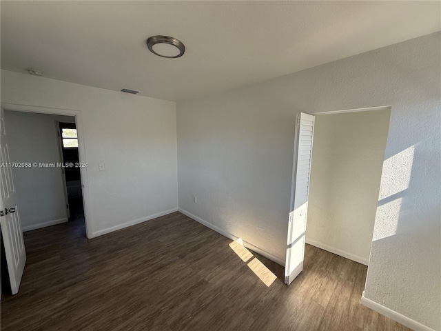 unfurnished room featuring dark wood-type flooring