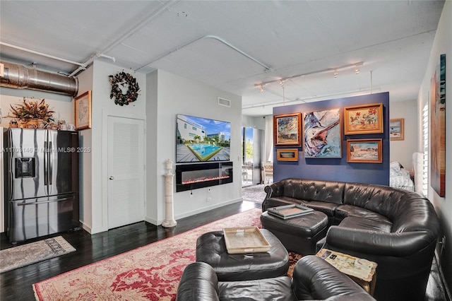 living room with dark hardwood / wood-style floors and rail lighting