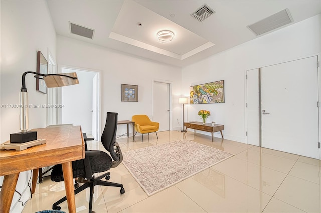 office with light tile patterned floors and a raised ceiling