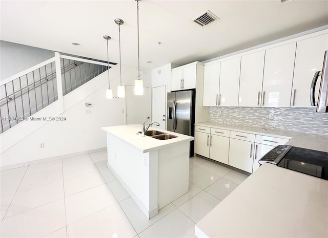 kitchen featuring a kitchen island with sink, sink, white cabinets, and pendant lighting