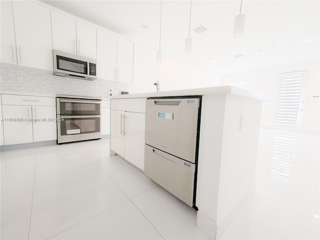 kitchen featuring white cabinetry, tasteful backsplash, pendant lighting, light tile patterned floors, and appliances with stainless steel finishes