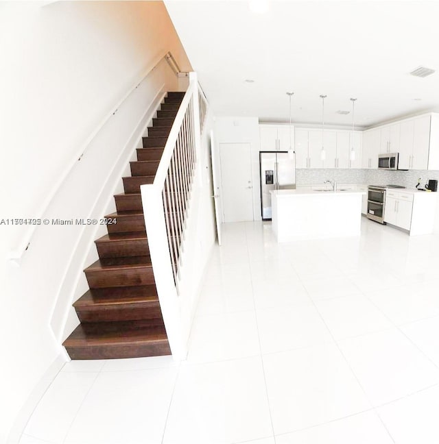 stairway featuring tile patterned floors and sink