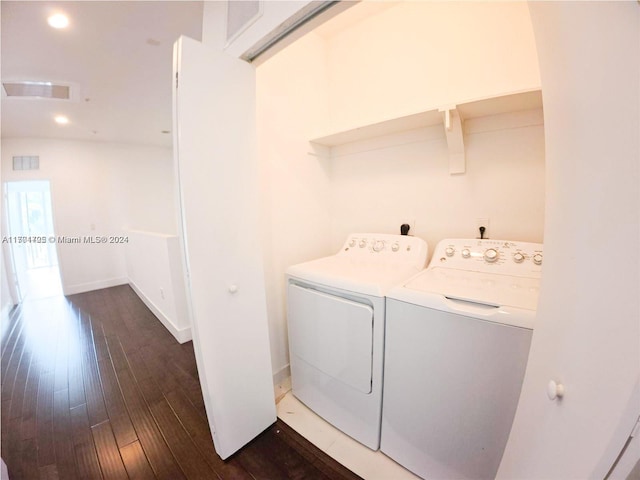 laundry area with washer and dryer and dark wood-type flooring