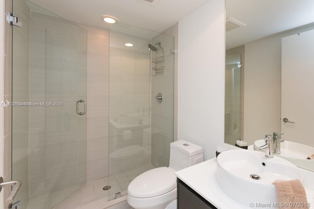 bathroom featuring a shower with door, vanity, and toilet