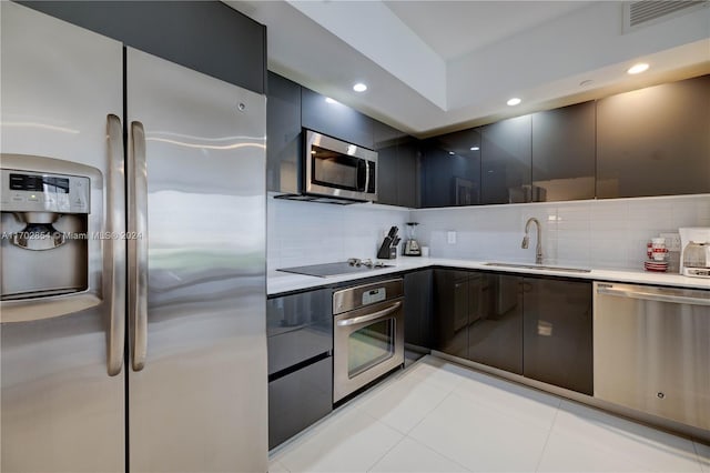 kitchen featuring light tile patterned floors, sink, appliances with stainless steel finishes, and tasteful backsplash