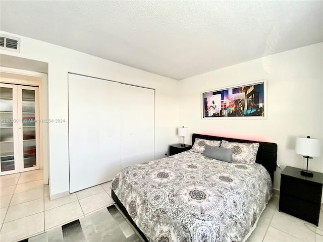 bedroom with light tile patterned floors, a textured ceiling, and a closet