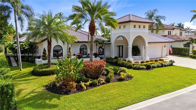 mediterranean / spanish home featuring a front yard and a garage