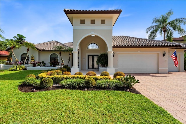 mediterranean / spanish home featuring a garage and a front yard