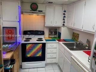 kitchen with electric range, sink, light tile patterned floors, stainless steel dishwasher, and white cabinets