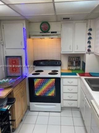 kitchen with white cabinets, white appliances, a drop ceiling, and light tile patterned flooring