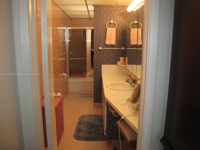 bathroom with tile patterned floors, a paneled ceiling, vanity, and bath / shower combo with glass door