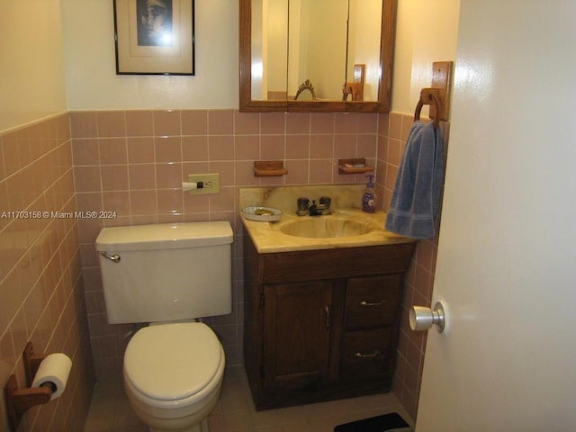 bathroom with vanity, toilet, and tile walls