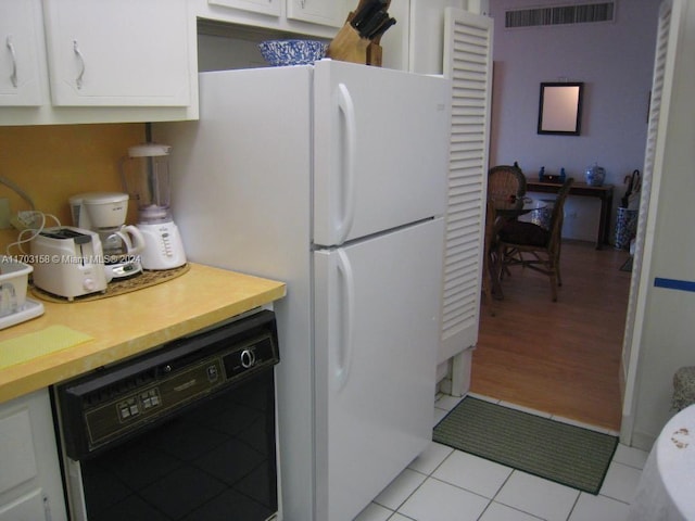 kitchen with white fridge, light hardwood / wood-style floors, white cabinetry, and black dishwasher