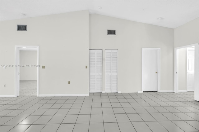 empty room featuring light tile patterned floors and high vaulted ceiling