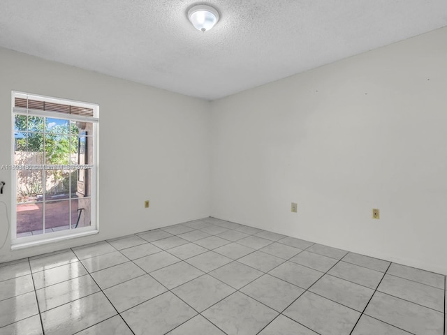 spare room with a textured ceiling and light tile patterned flooring