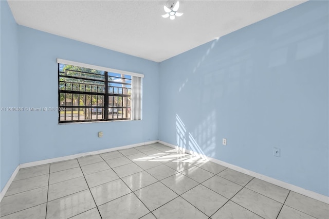 spare room with light tile patterned flooring and a textured ceiling