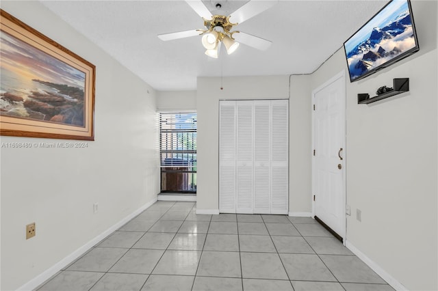 interior space featuring ceiling fan, light tile patterned flooring, and a textured ceiling