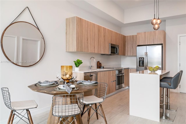 kitchen with appliances with stainless steel finishes, a breakfast bar, sink, pendant lighting, and a center island