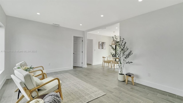 living area with light wood-type flooring, visible vents, baseboards, and recessed lighting