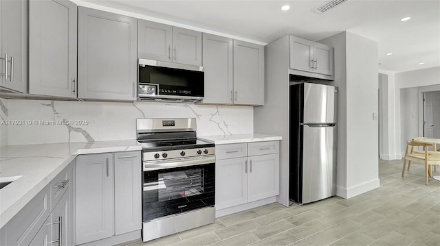 kitchen featuring appliances with stainless steel finishes, gray cabinets, and visible vents