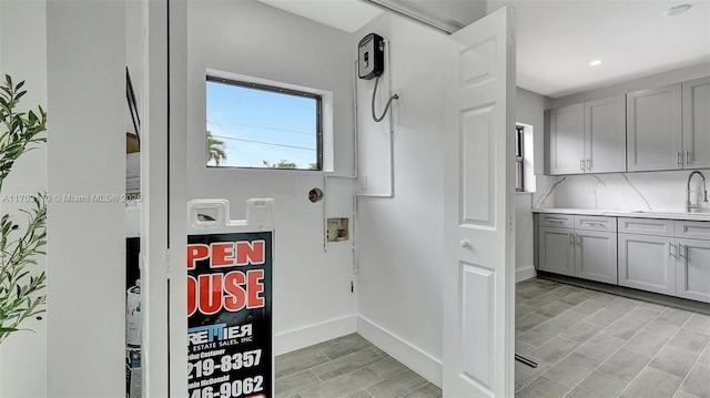 clothes washing area with baseboards, wood finish floors, washer hookup, a sink, and recessed lighting