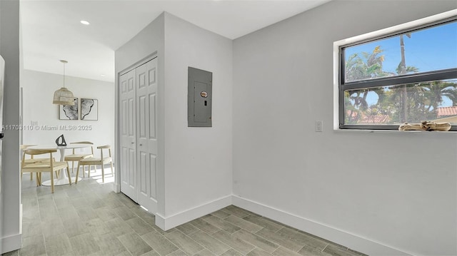 corridor featuring wood finish floors, electric panel, and baseboards