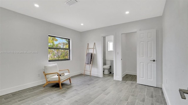 sitting room with light wood-type flooring, plenty of natural light, visible vents, and baseboards