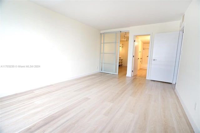 unfurnished bedroom with ensuite bath and light hardwood / wood-style flooring