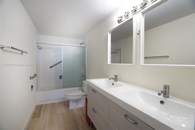 full bathroom with hardwood / wood-style floors, vanity, toilet, and bath / shower combo with glass door