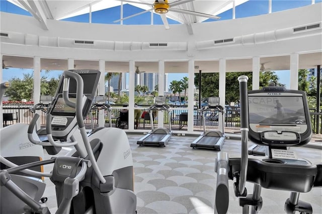 exercise room with a wealth of natural light, ceiling fan, carpet floors, and a high ceiling